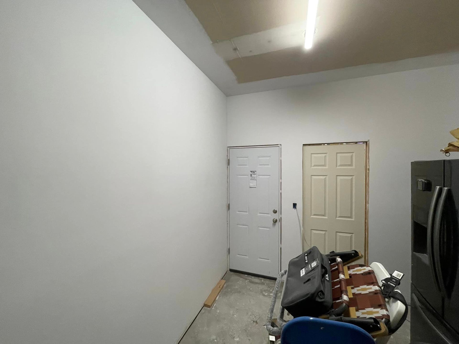 A room with a door and a refrigerator in it.