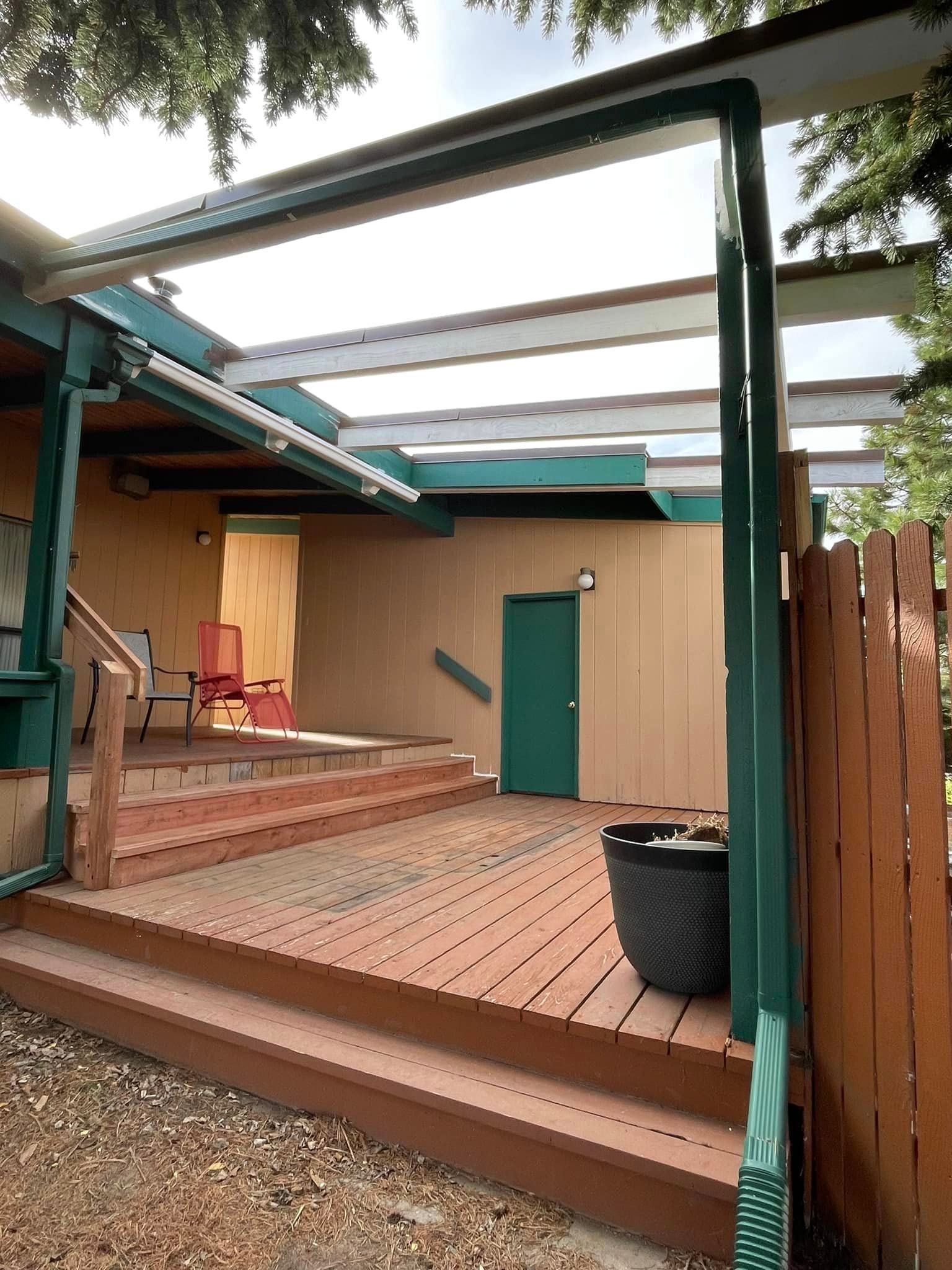 A wooden deck with stairs leading up to it and a pergola over it.