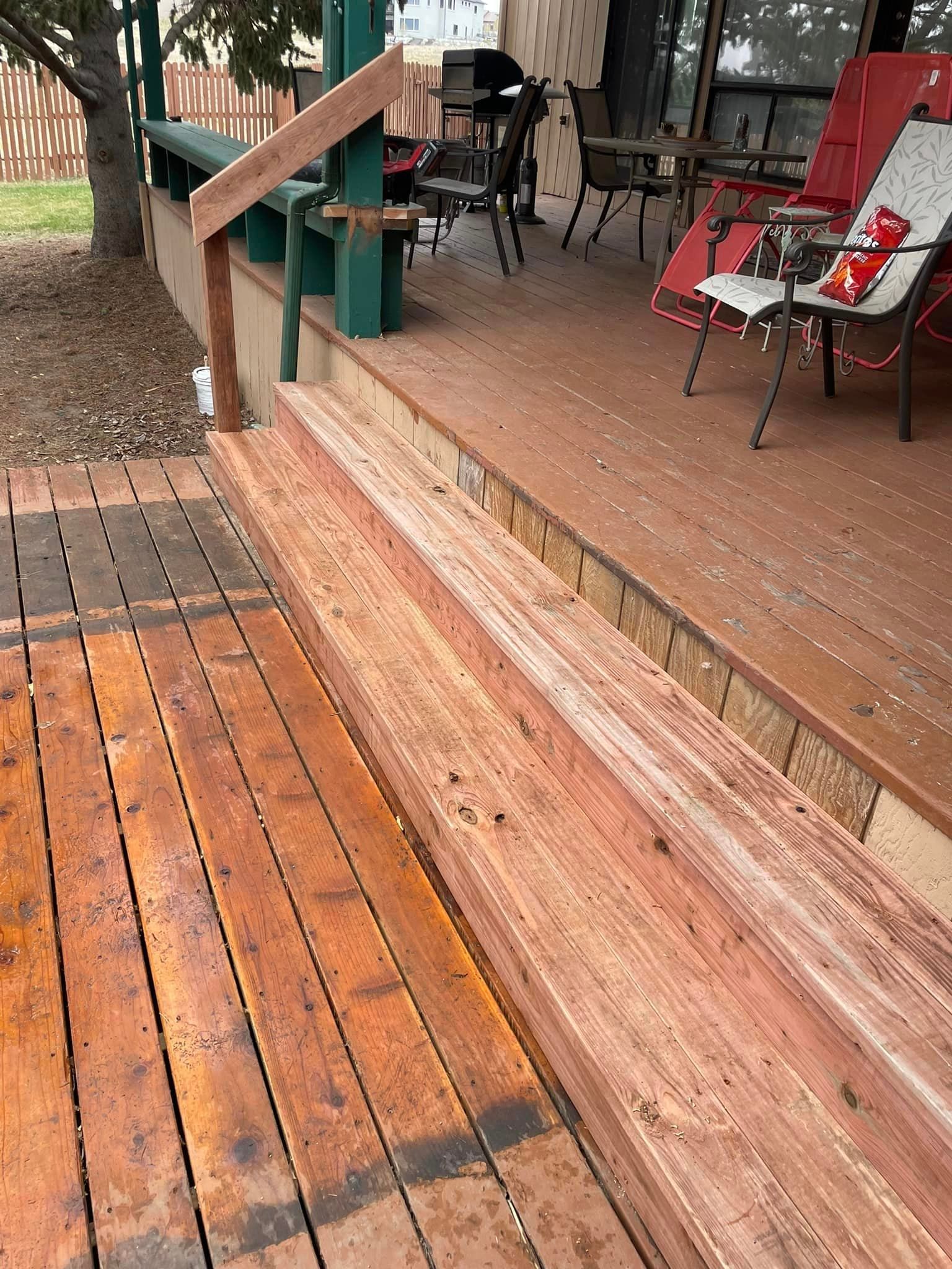 A wooden deck with stairs and chairs on it.