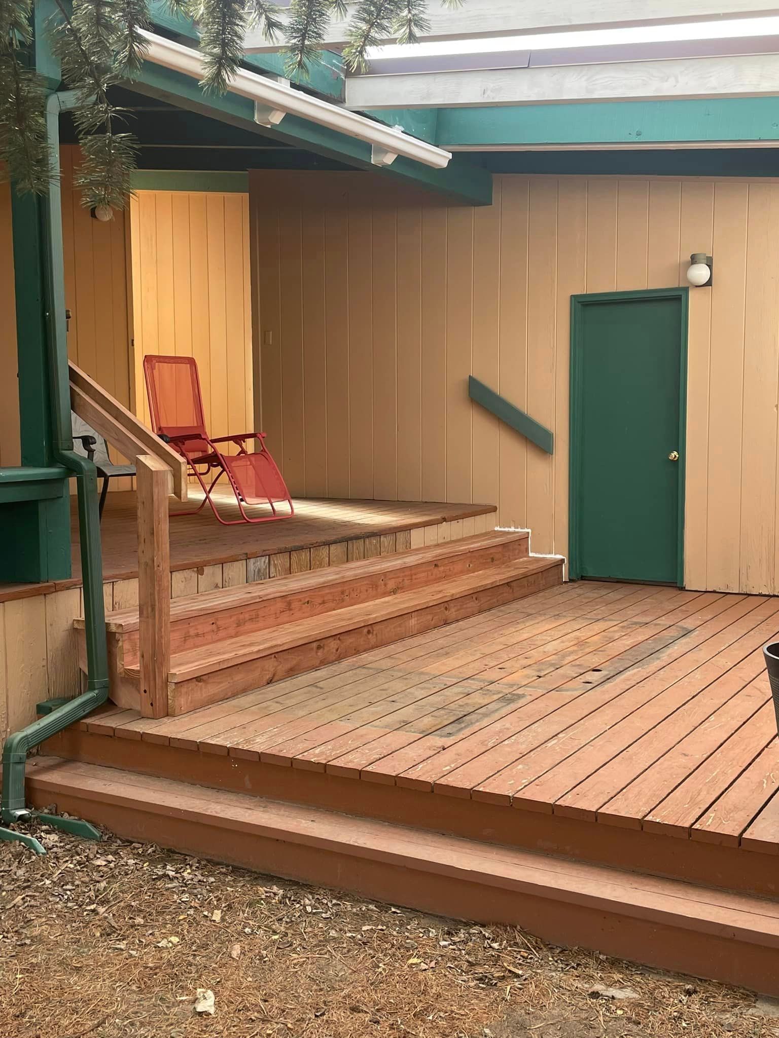 A wooden deck with stairs and a chair on it in front of a house.