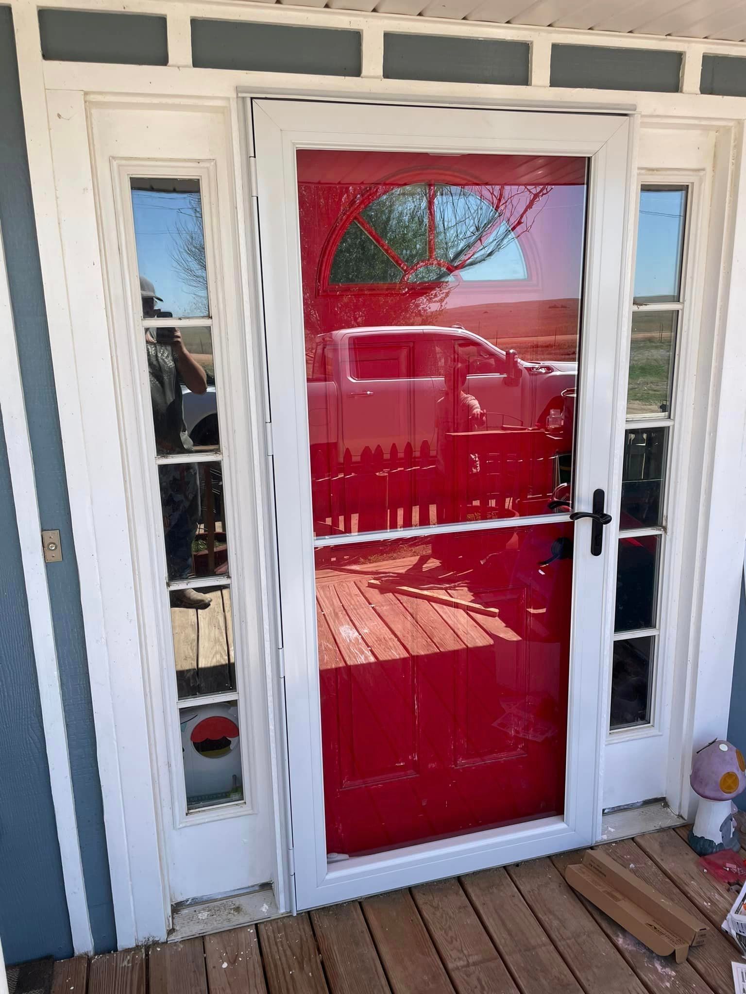 A red door with a white frame is sitting on a wooden deck.