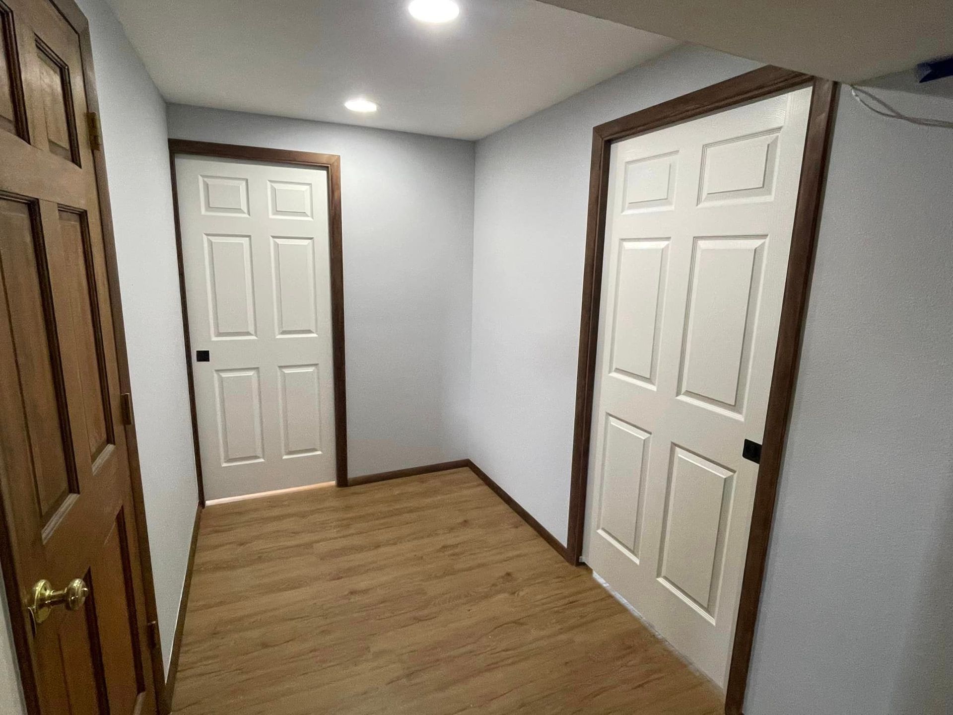 A hallway with two white doors and wooden floors.