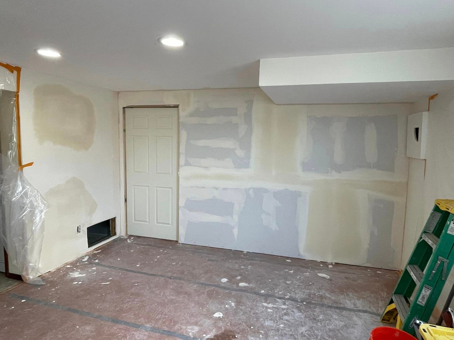 A room with a ladder on the floor and a door.