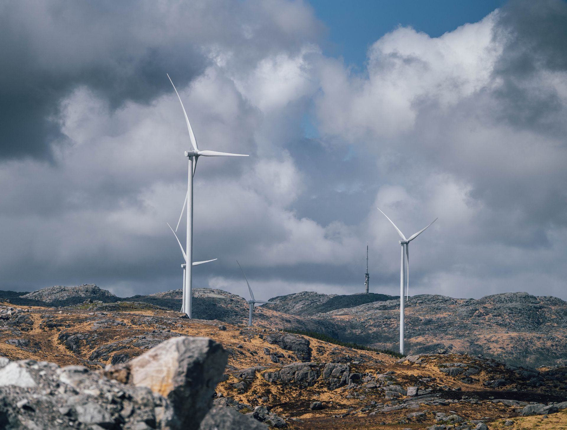 Vindturbiner i et steinete, kupert landskap under en overskyet himmel.