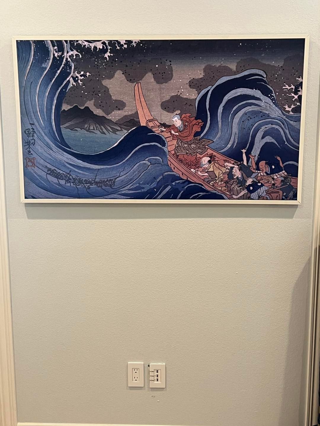 A painting of a boat in the ocean is hanging on a wall.