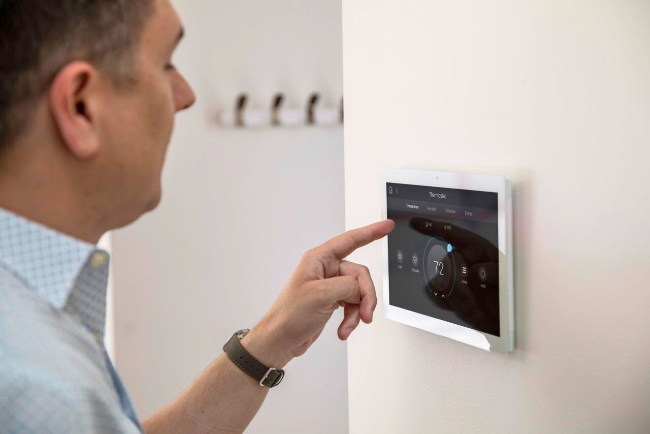 A man is using a smart device on a wall. Portfolio for Premier Lighting & Home Automation in Dallas Fort Worth (DFW).