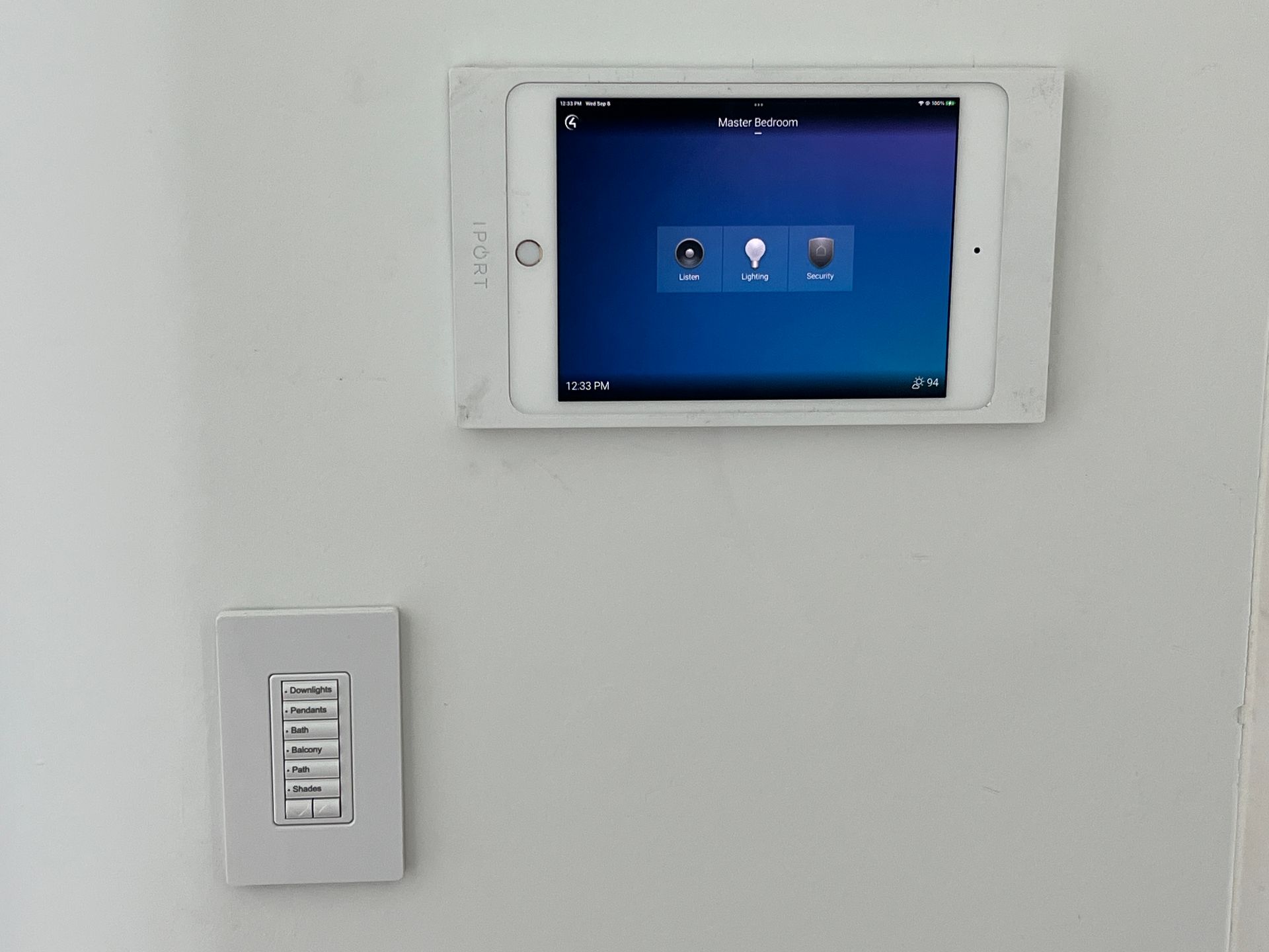 A tablet is mounted on a wall next to a light switch