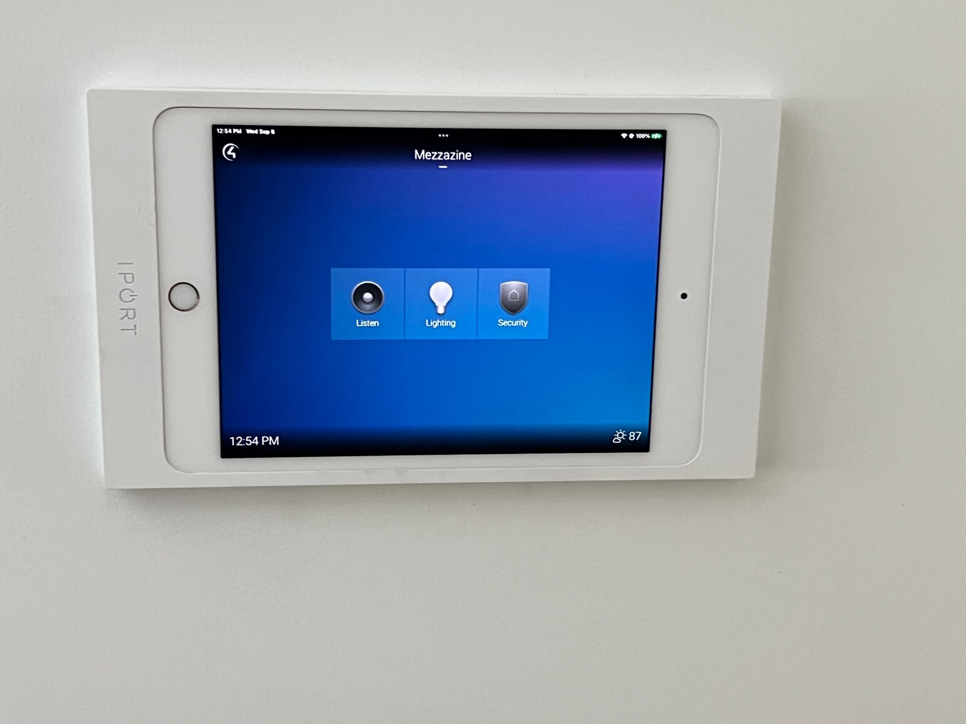 A tablet with a blue screen is mounted on a wall