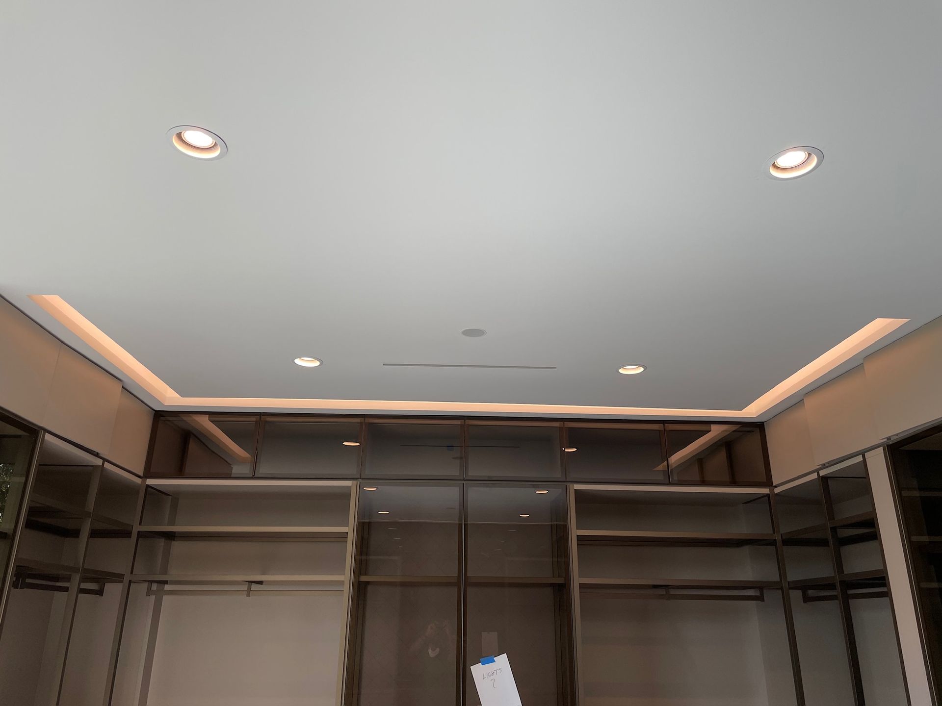A walk in closet with a white ceiling and lots of shelves