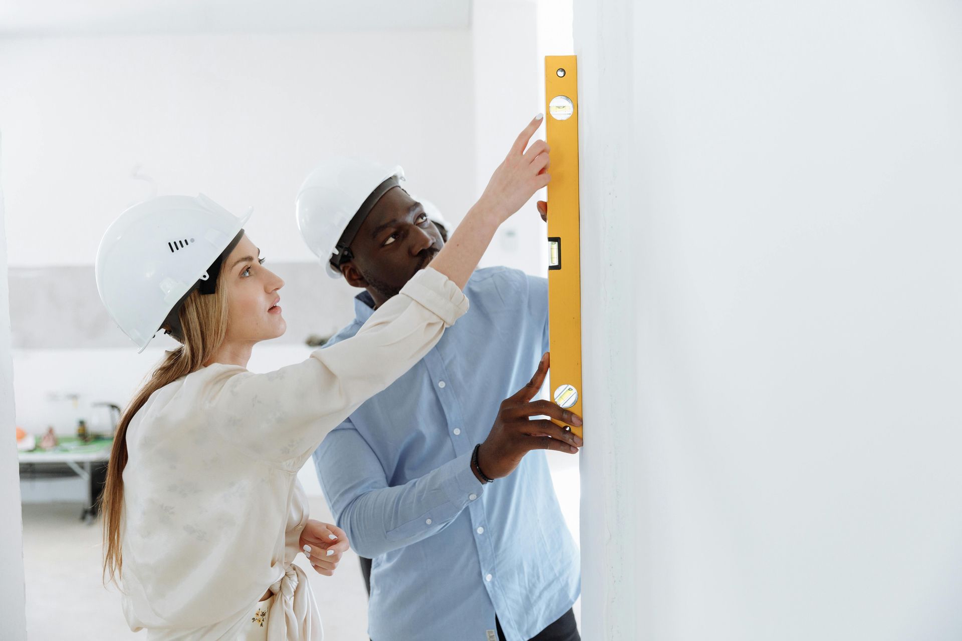 A man and a woman are measuring a wall with a level. Portfolio for Premier Lighting & Home Automation in Dallas Fort Worth (DFW).