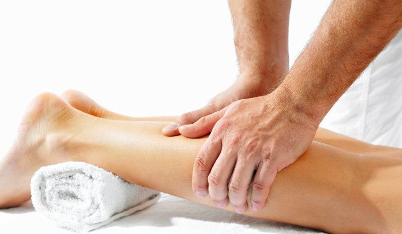 Un hombre le está dando un masaje en las piernas a una mujer.