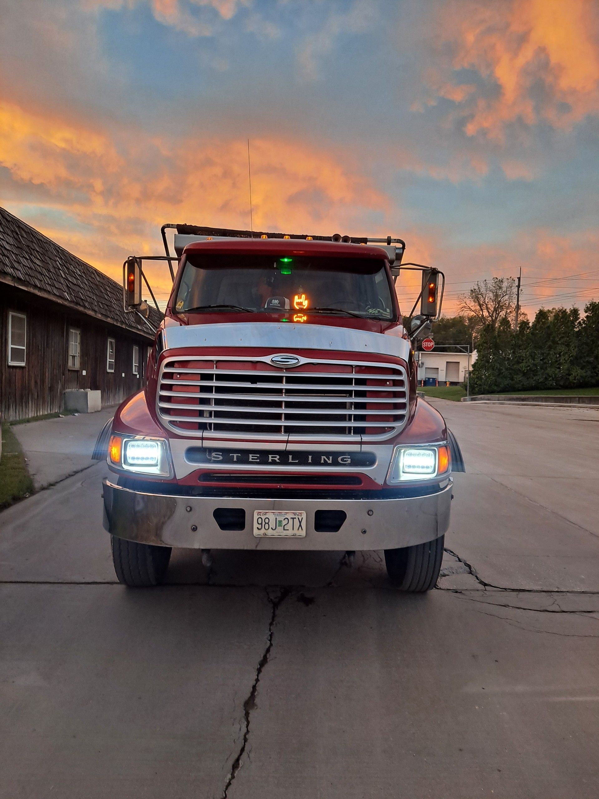 A semi-truck carrying stacks of lumber on a highway under a blue sky.