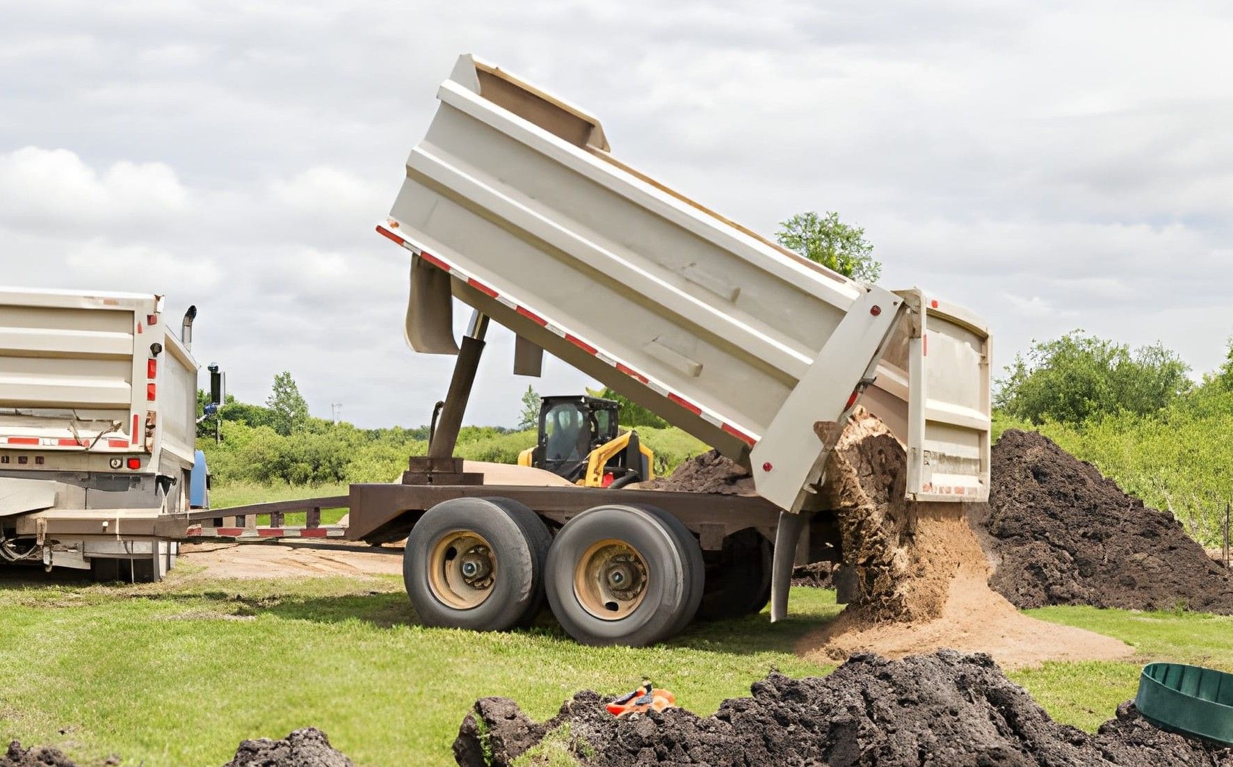 Orange excavator clearing debris, trees in background.