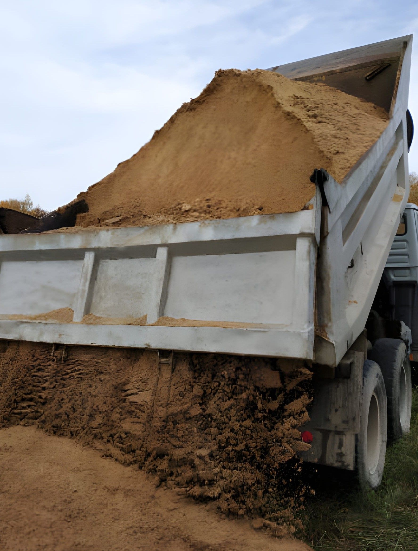 Pile of debris including wood and broken concrete, in front of a green ivy-covered fence.