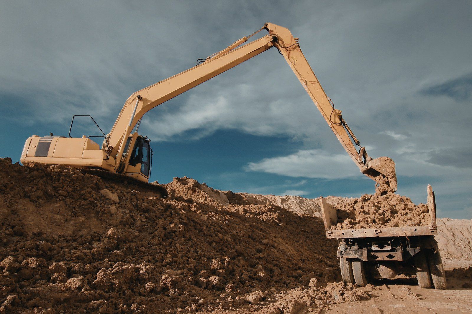 Person with red gloves shovels debris outdoors.