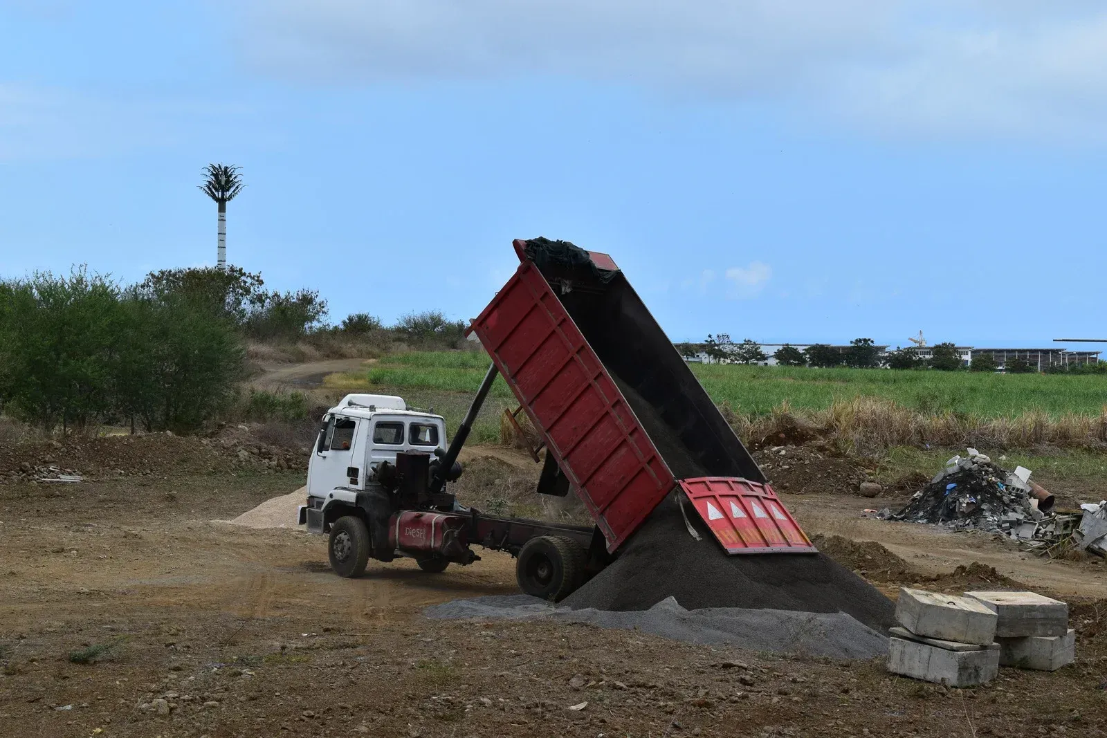 Pile of demolition debris with heavy machinery in a clearing.