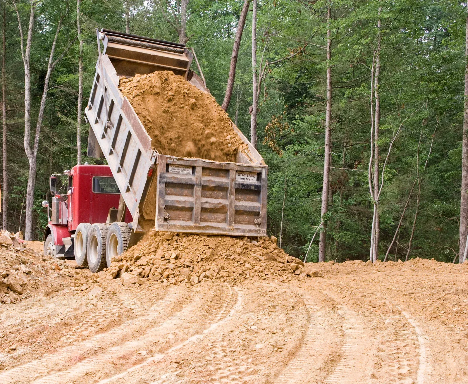 Yellow construction vehicles moving earth at an open-pit mine under a bright blue sky.