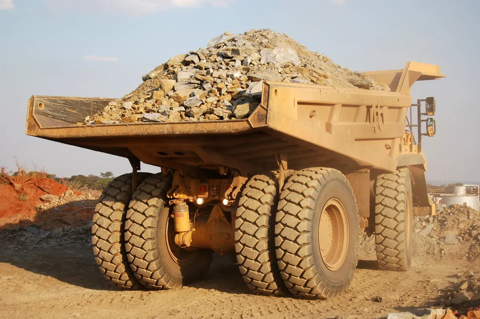 Large yellow dump truck loaded with rocks on a dirt road in a quarry.