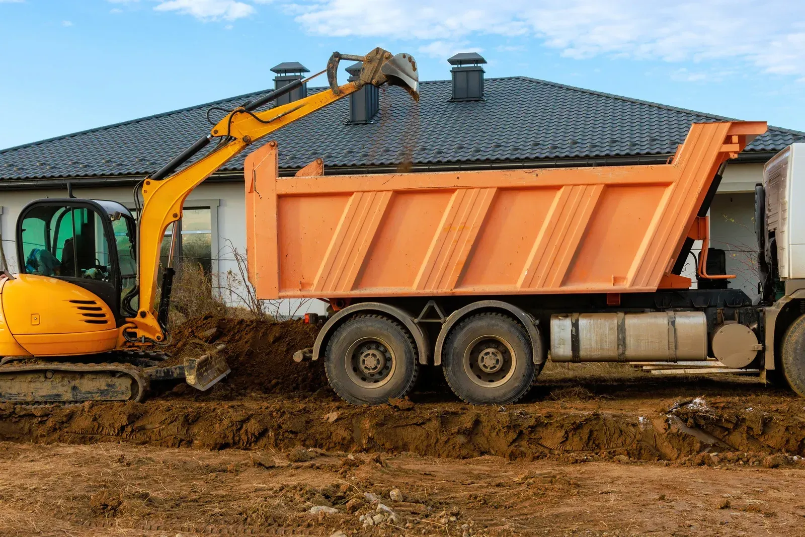 Overhead view of a blue and yellow excavator on a brown construction site.