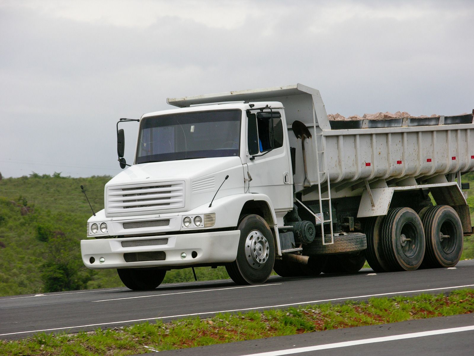 Pile of construction debris; gray concrete and tile against a blurred green background.