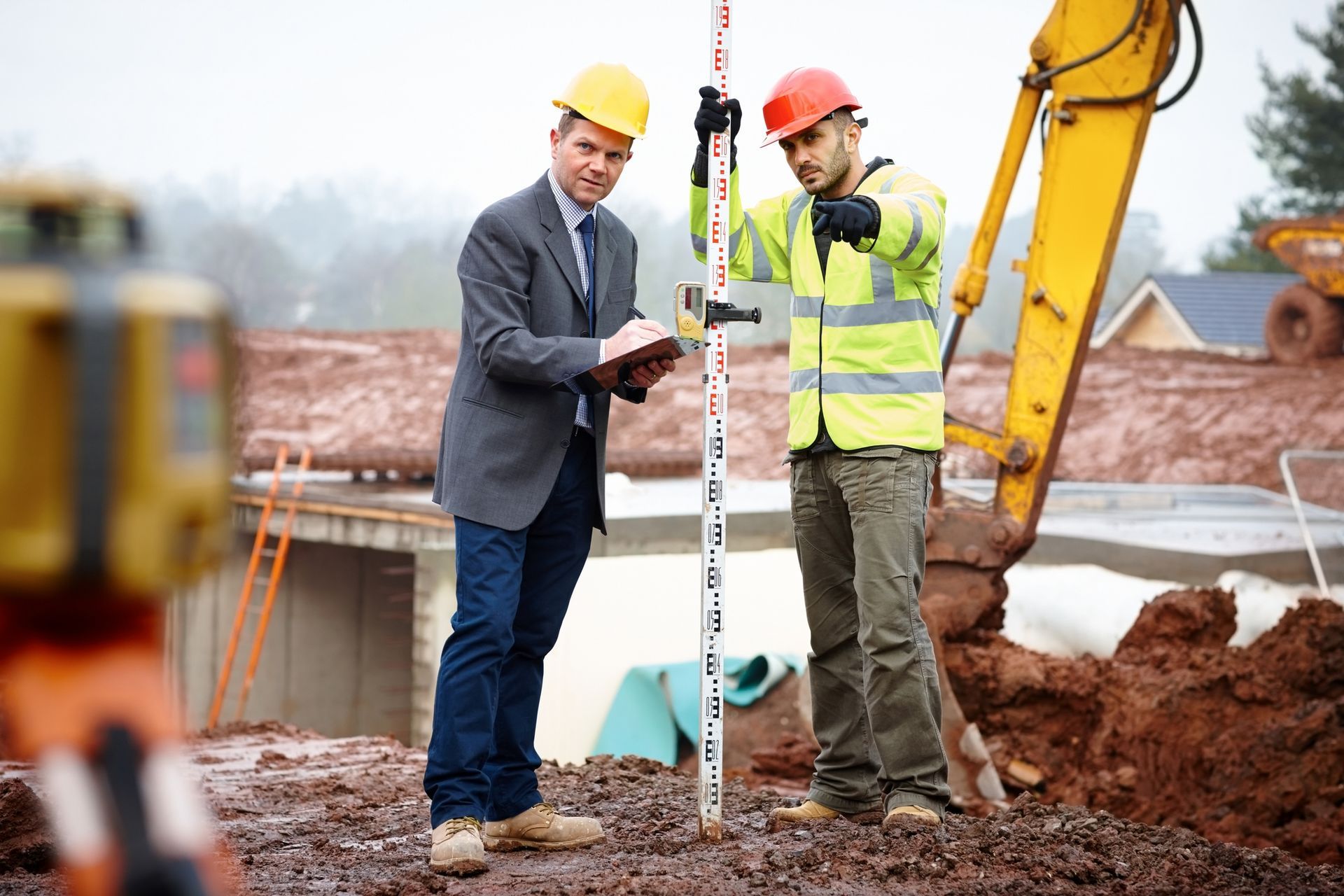 Two construction workers on a muddy construction site.