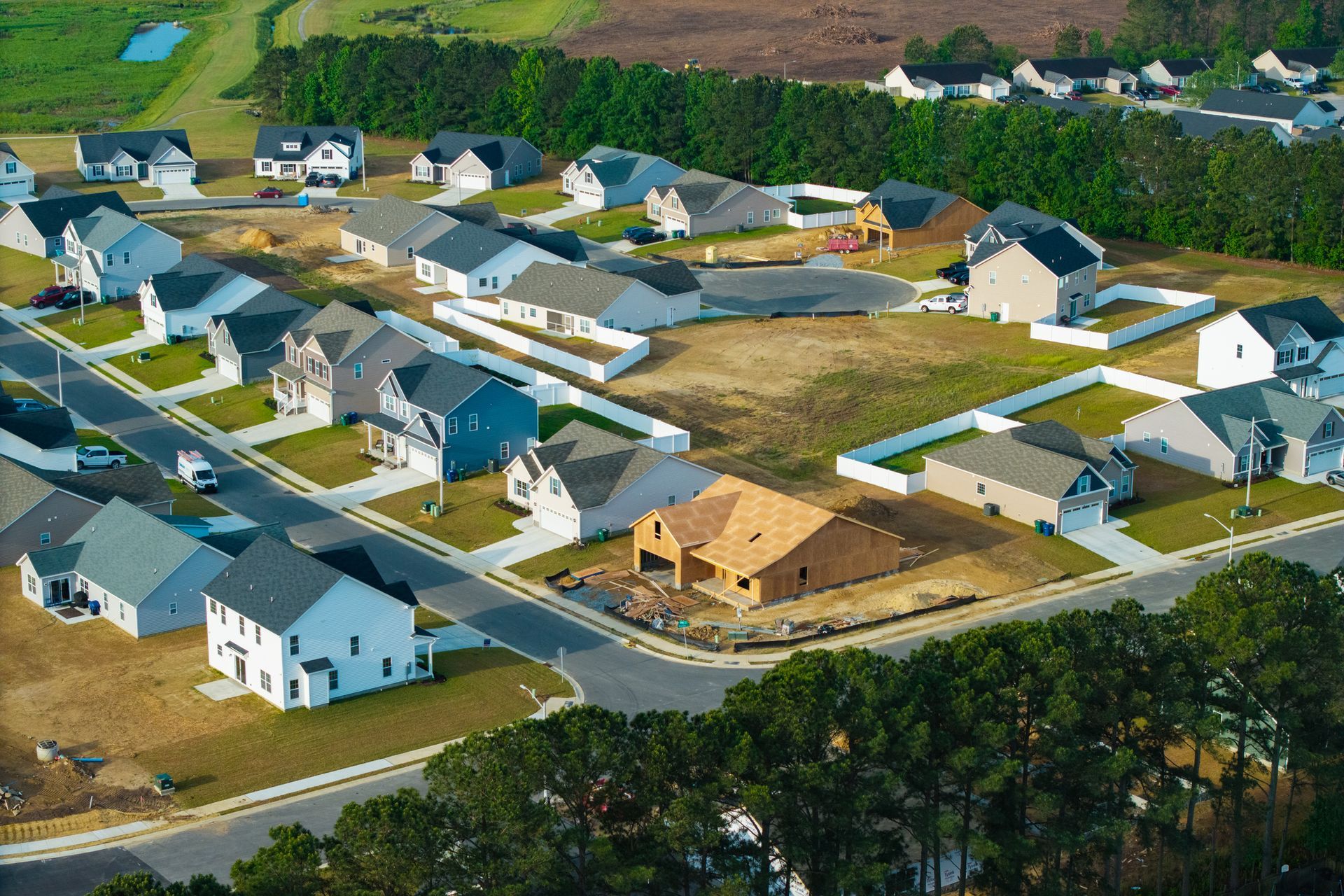 Aerial view of a suburban neighborhood with newly built houses, construction, and green spaces.