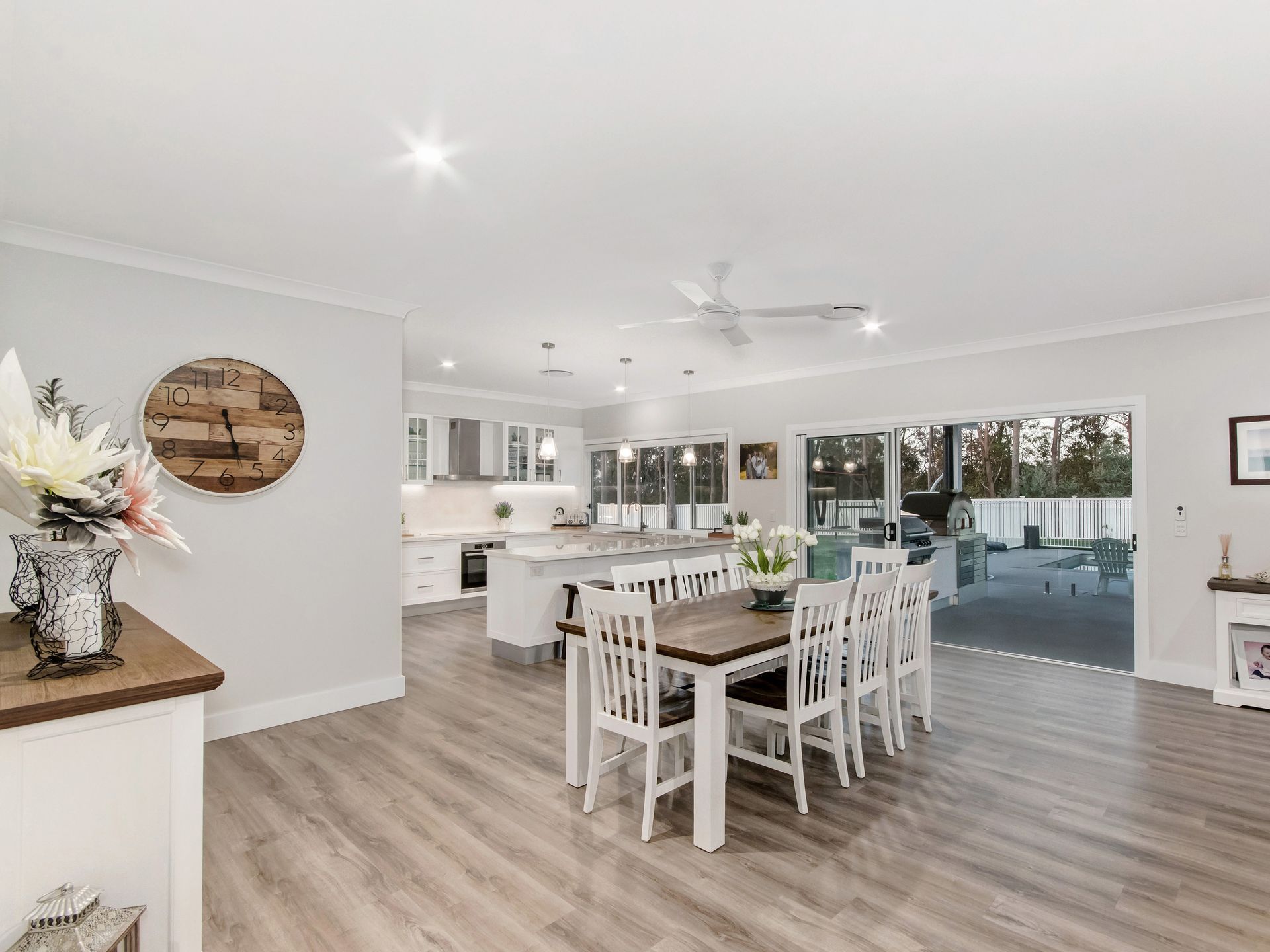 A bright, modern open-plan kitchen and dining area featuring a wooden table, white chairs, and light wood flooring — Michael Duncan Constructions Pty Ltd in Robina, QLD