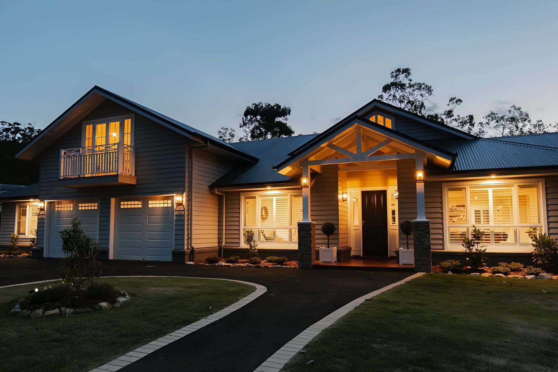 A two-story suburban house with a lit porch and driveway at twilight — Michael Duncan Constructions Pty Ltd in Robina, QLD