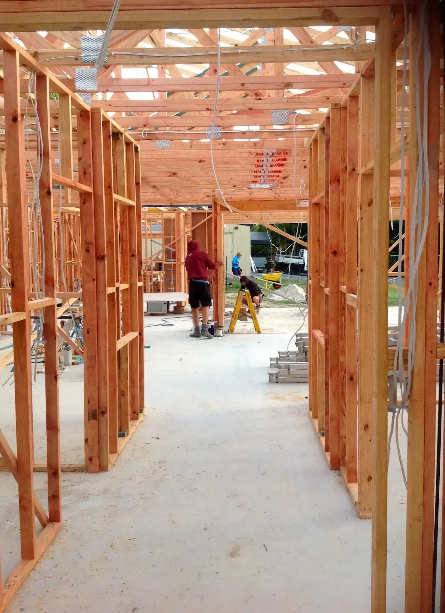 Two people work inside the wood-framed structure of a building under construction with a concrete floor. — Michael Duncan Constructions Pty Ltd in Mermaid Beach, QLD