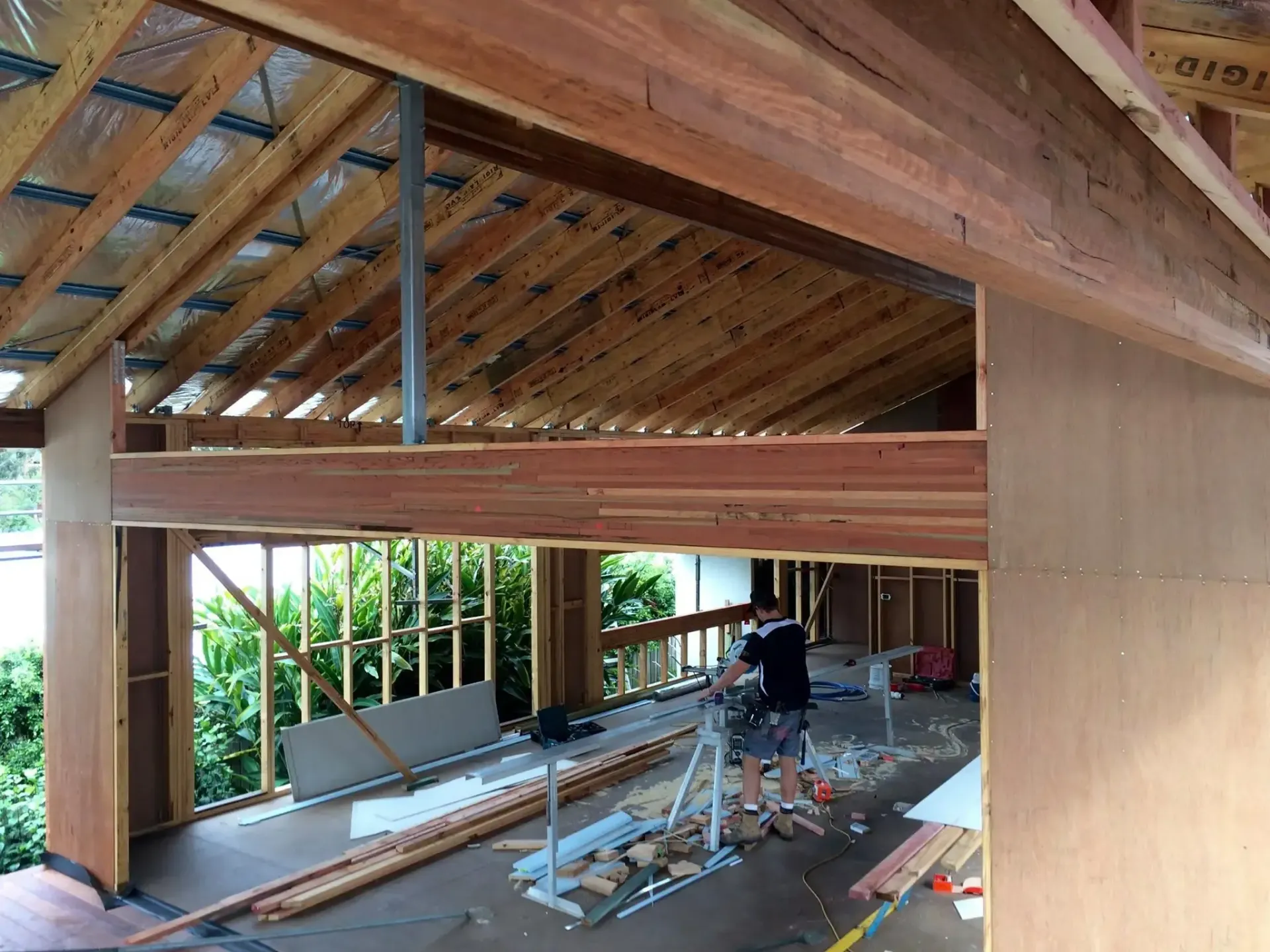 A construction worker builds a wood-framed structure with a visible rafter roof and large open doorway on a sunny day. — Michael Duncan Constructions Pty Ltd in Mermaid Beach, QLD