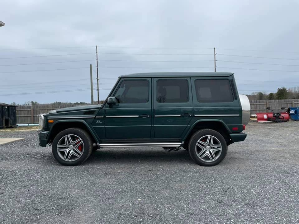Green Mercedes-Benz G-Class SUV parked outdoors, with silver rims and a spare tire on the back.