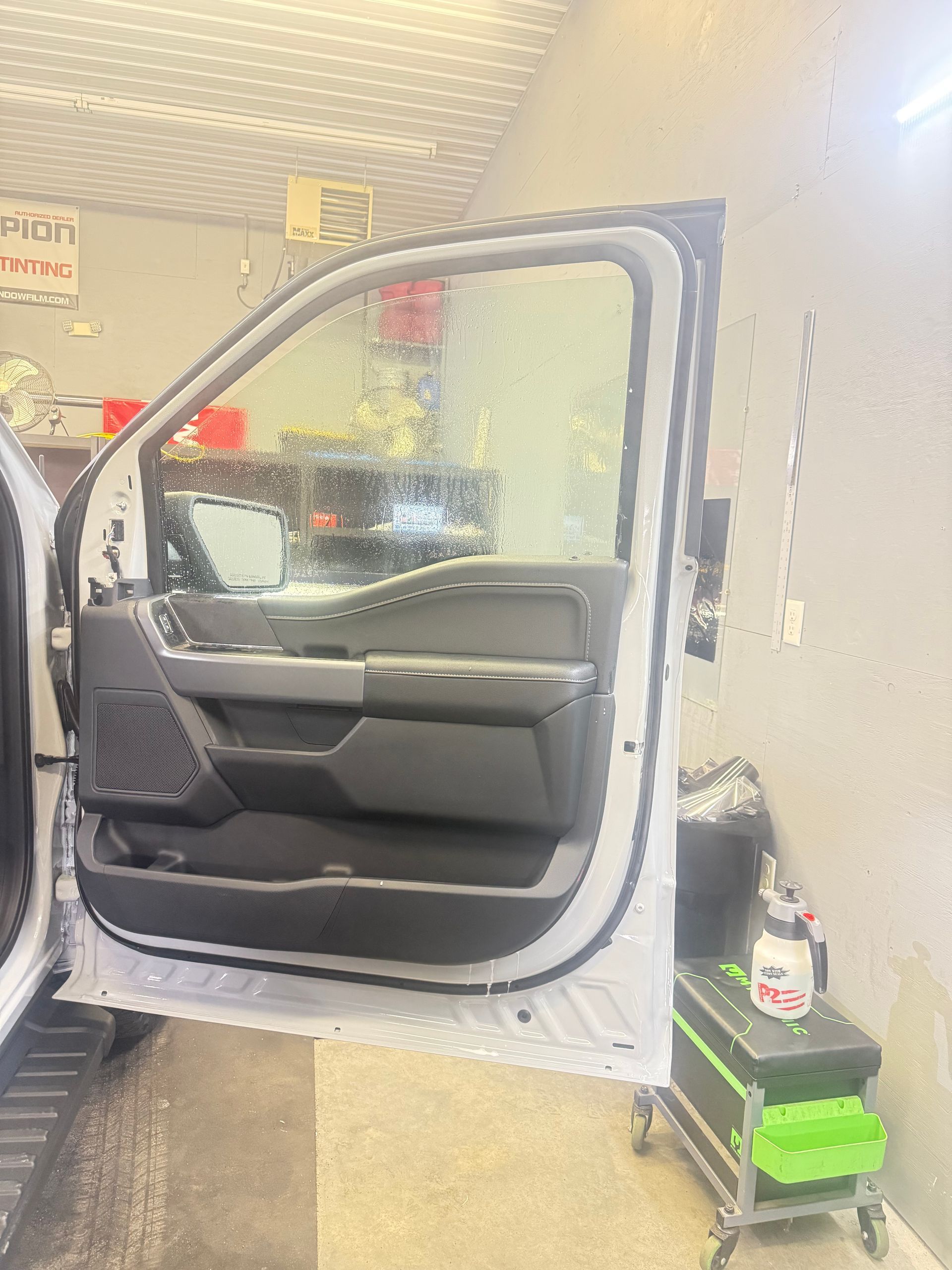 Open white car door in a garage, revealing interior.