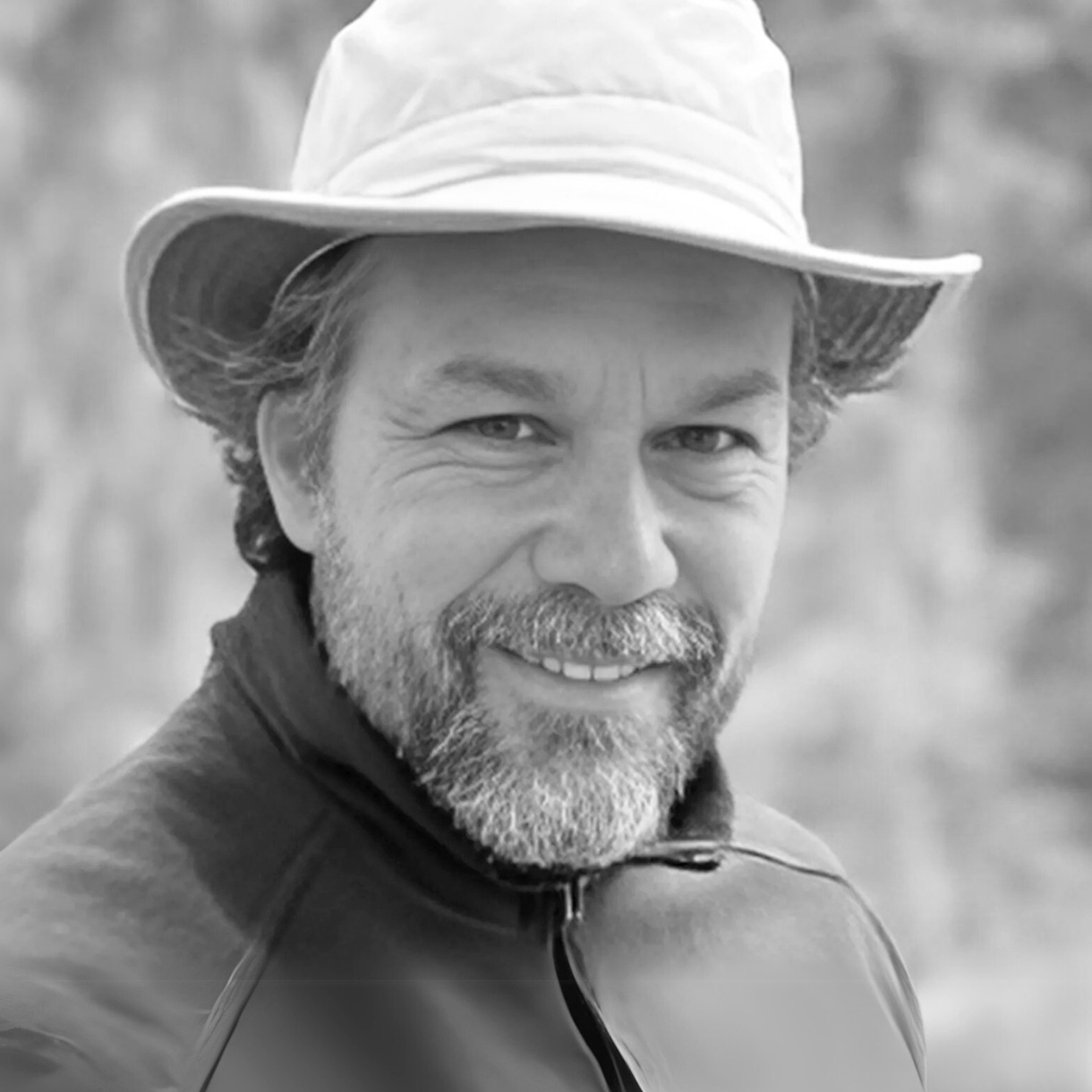 Man wearing a hat and jacket, smiling at the camera.