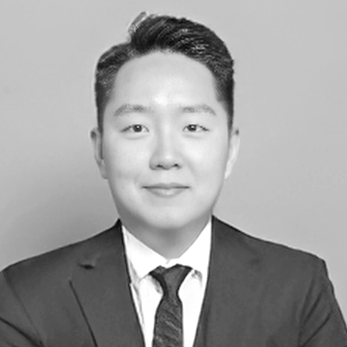 Man in a suit smiles, posed for a headshot. Black and white.