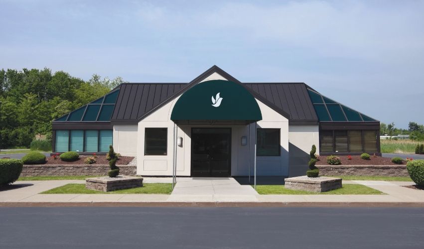 A white building with a green awning and a bird on it