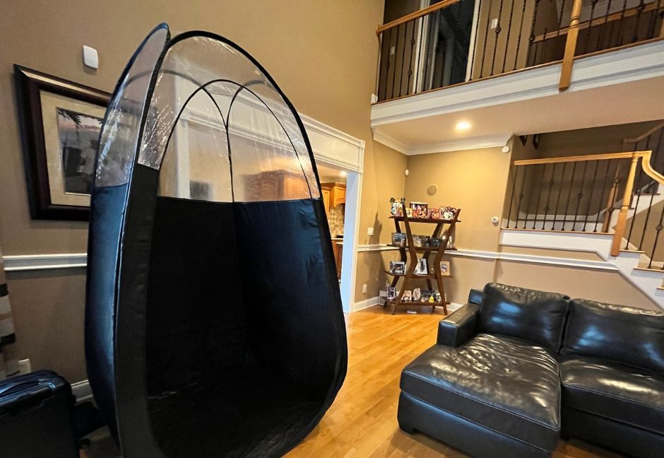 Black spray tanning tent in a living room.
