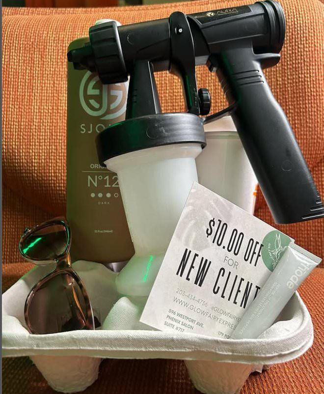 Spray tan gun and supplies in a carrier; sunglasses, lotion, and a 