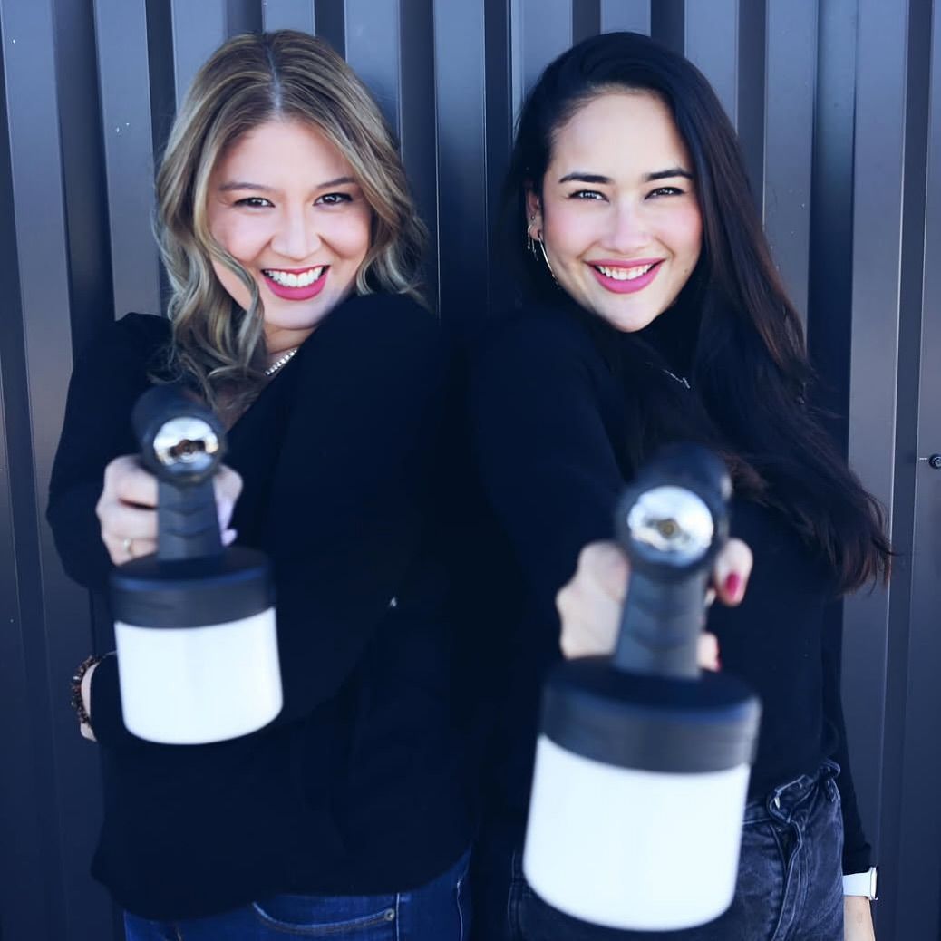 Woman with scissors, surrounded by hands holding hair tools, dark background.