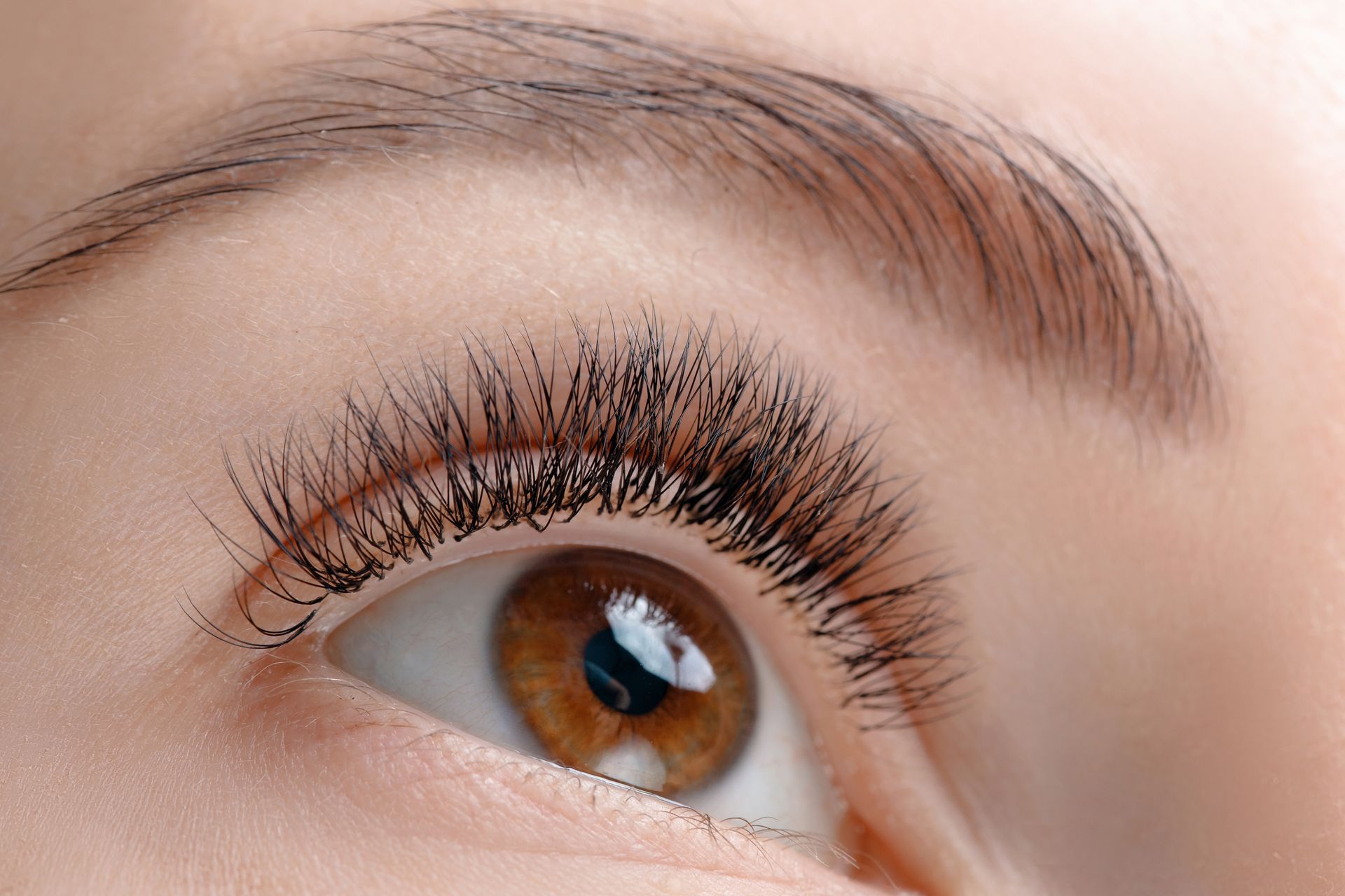 Woman with auburn hair smiles in front of a neon 