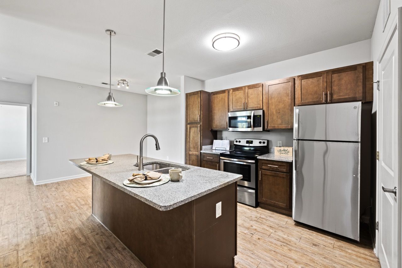 Kitchen with island, granite counters, stainless steel appliances, and dark wood cabinets.