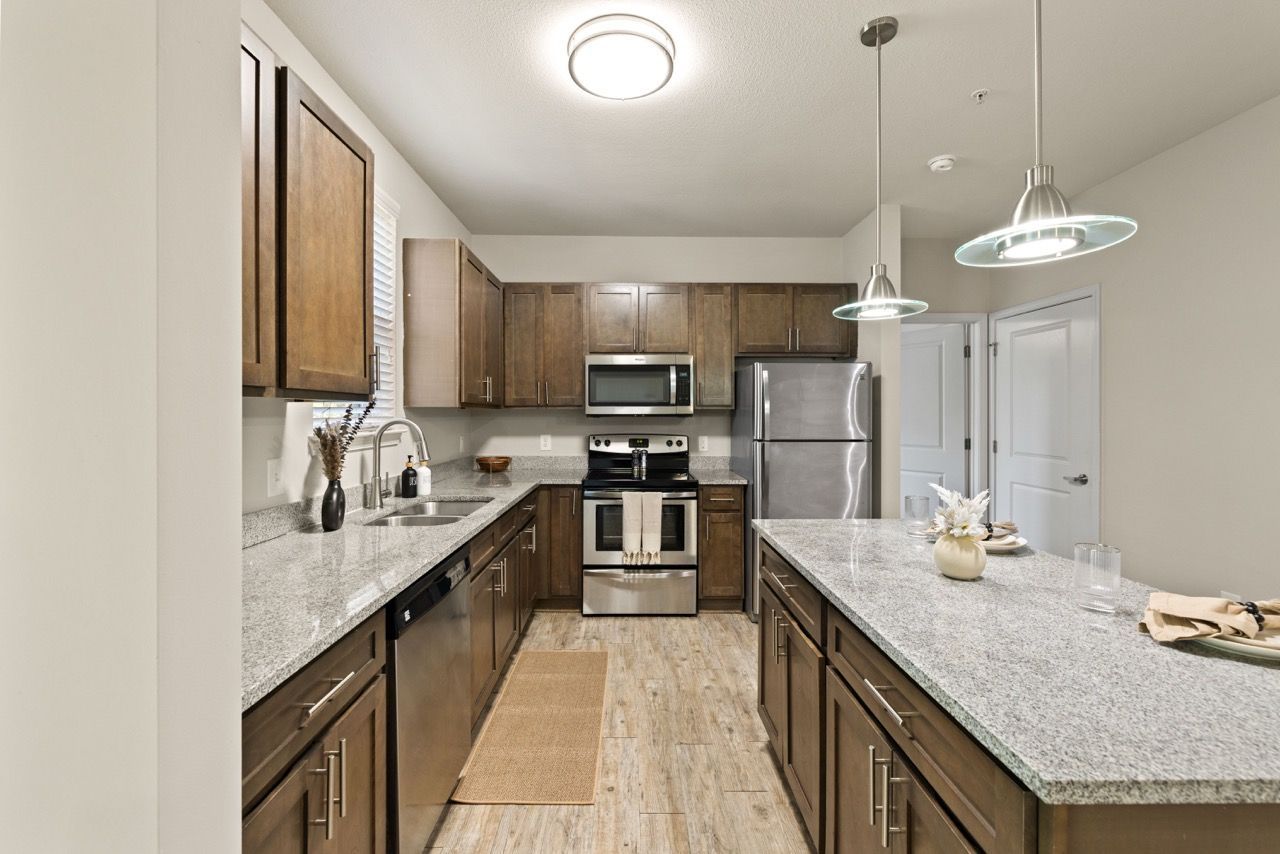Modern apartment kitchen with granite countertops, stainless steel appliances, and an island.