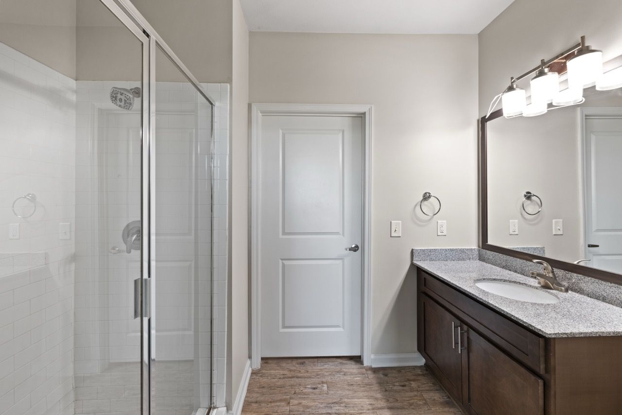 Bathroom with a glass-enclosed shower, single-sink vanity, and doorway.
