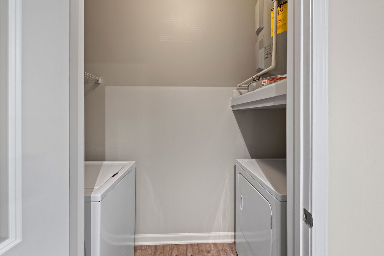 Laundry closet with a washer and dryer and utility shelving above.