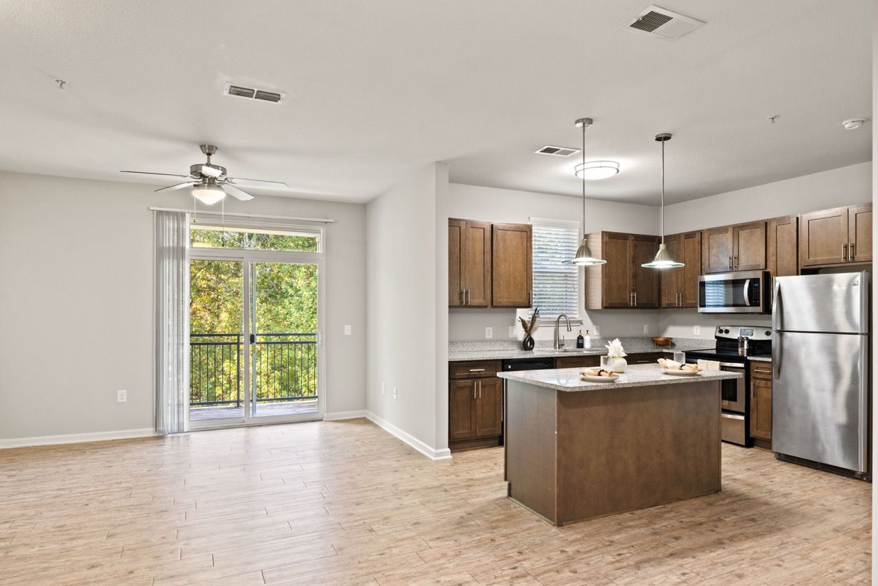 Open-concept kitchen with island, stainless appliances, and sliding balcony door.