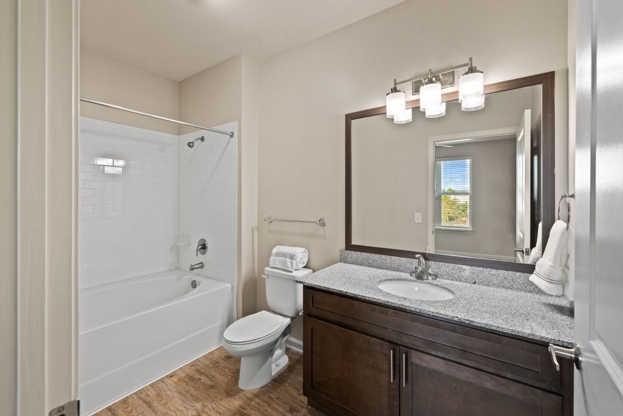 Apartment bathroom with vanity, mirror, towel bar, toilet, and tub/shower.