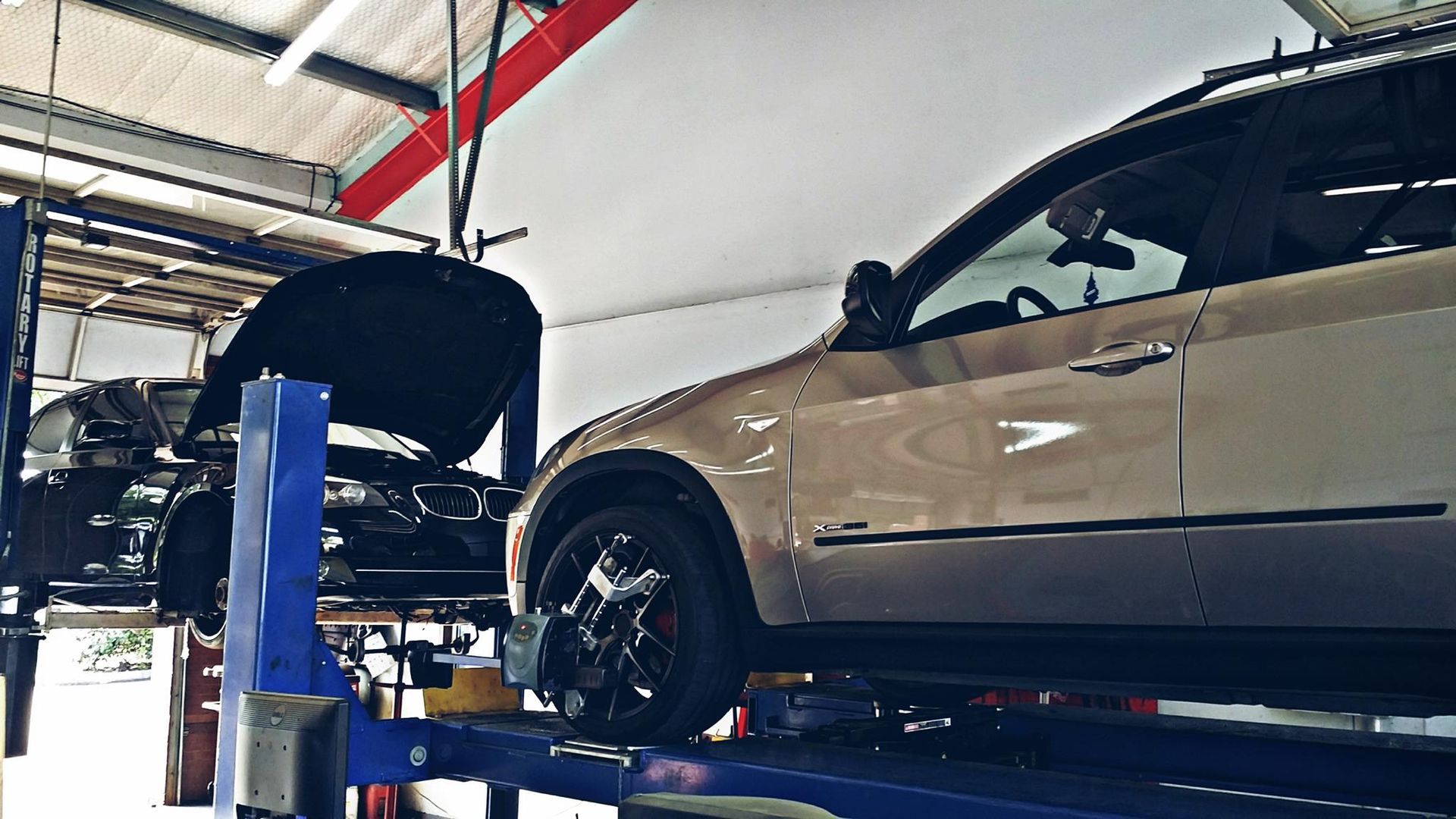 Two SUVs on car lifts inside a garage. One has its hood open.