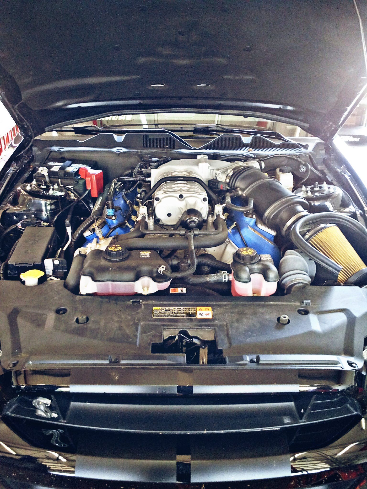 Black car engine compartment with a supercharger.