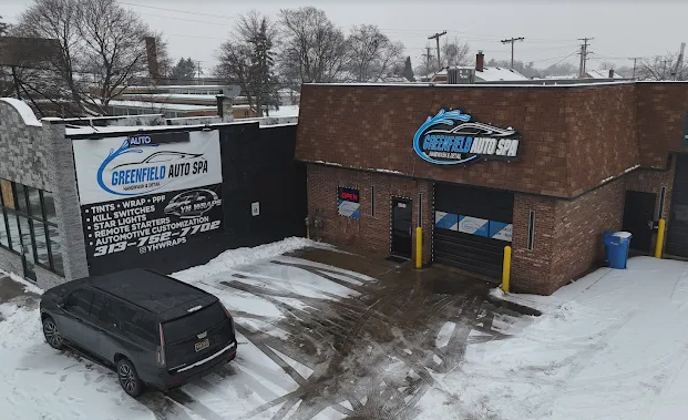 A black van is parked in front of a car wash in the snow.