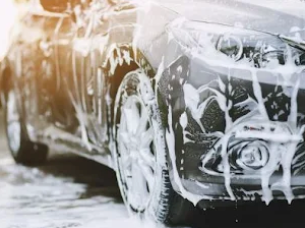 A car is covered in foam while being washed.