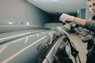 A man is polishing a car with a machine.